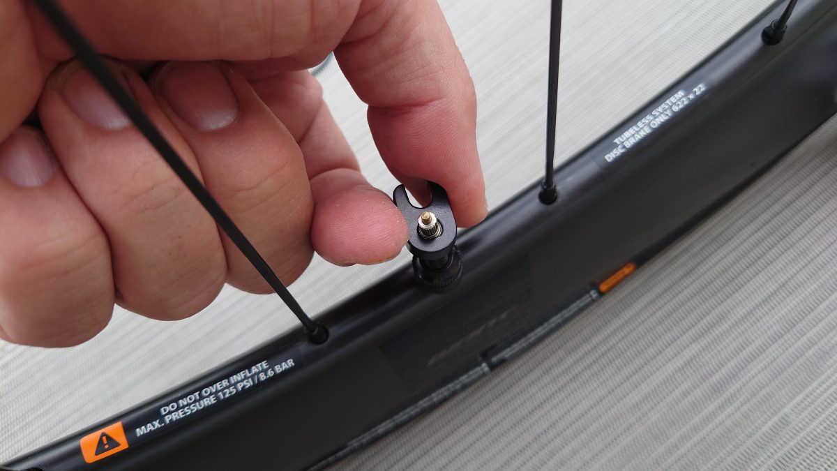 a hand holding a screw on a black device